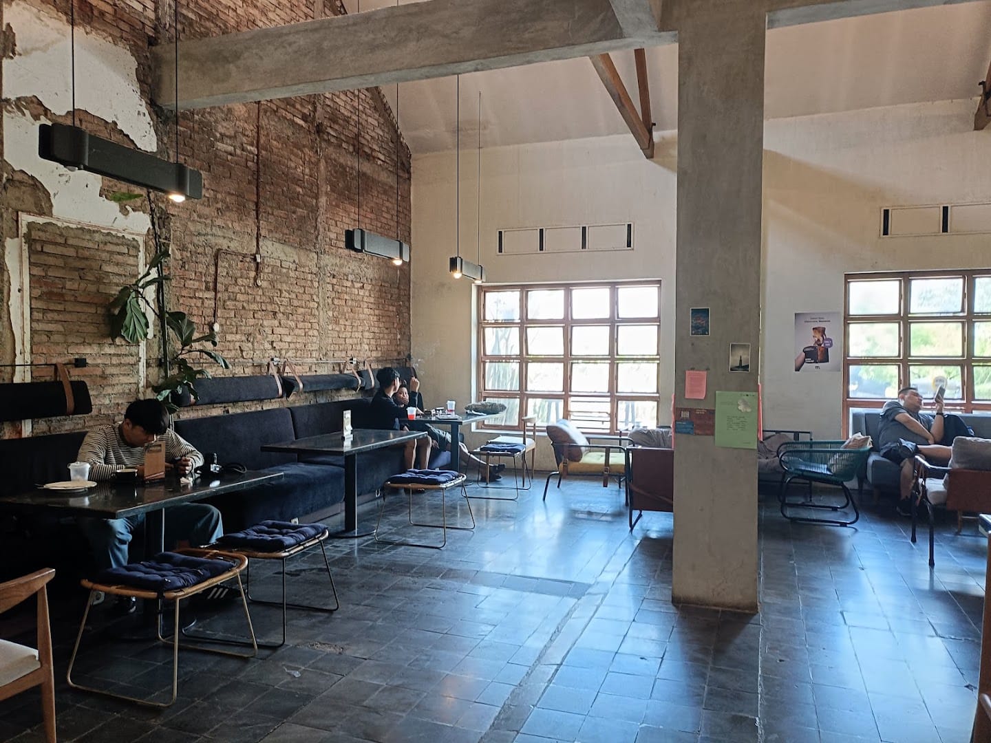 Exposed brick interior of Monday Co Dago, customers working at heritage tables