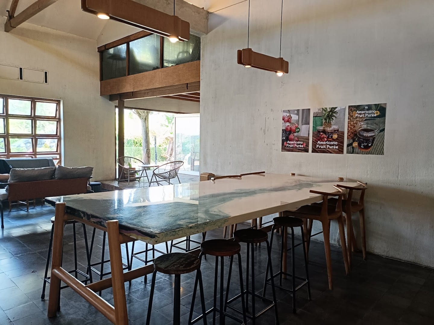 Interior of Monday Co Dago — pitched ceiling, marble bar table, wooden stools, late afternoon light